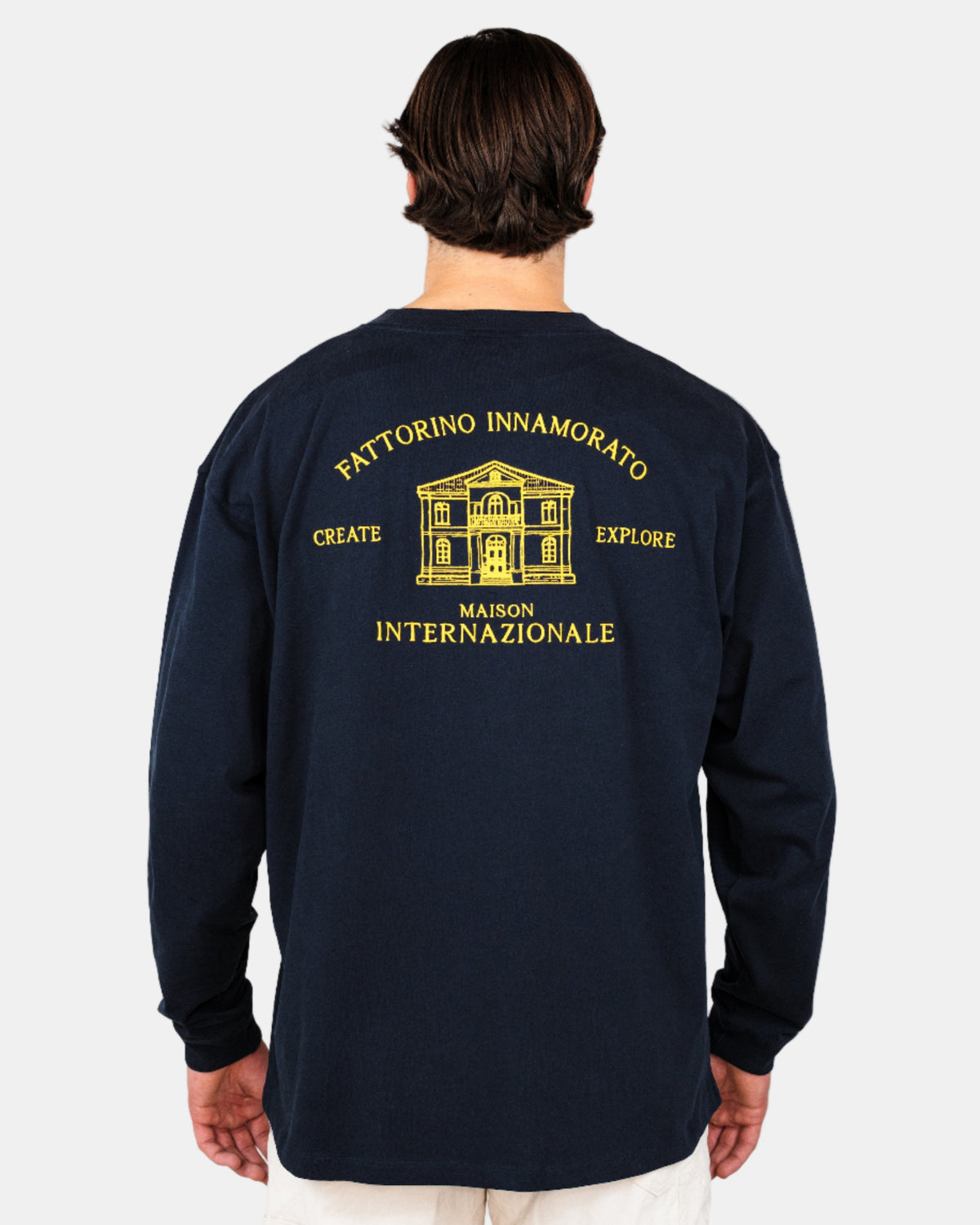 Person wearing a navy blue long-sleeve shirt with yellow text and graphics on the back against a white background. Fattorino navy maison longsleeve