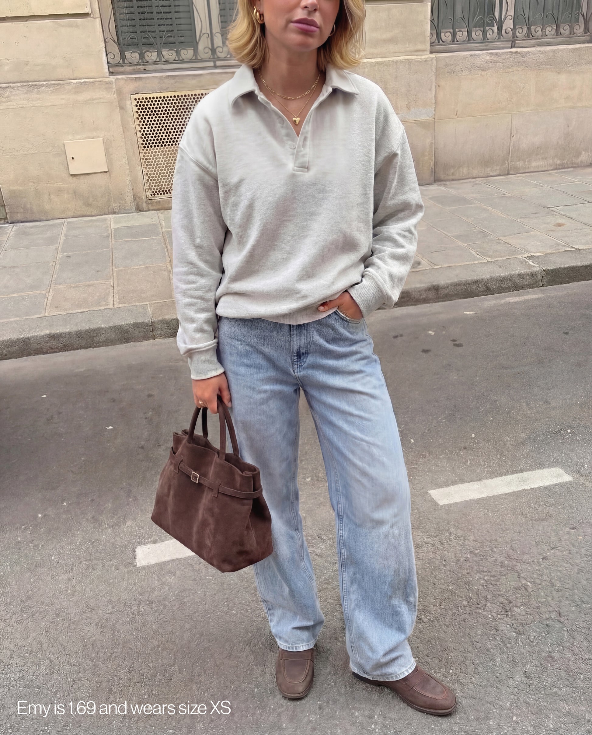 Girl wearing a light gray fattorino rugby sweater, light blue jeans, and brown shoes on a street.
