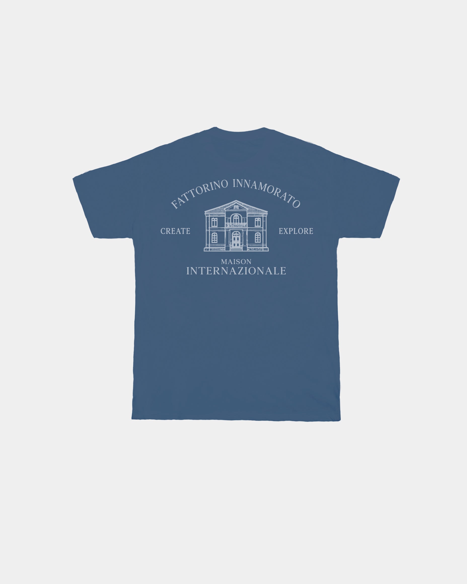 Blue t-shirt with white text and building graphic on a light gray background. Fattorino innamorato maison blue