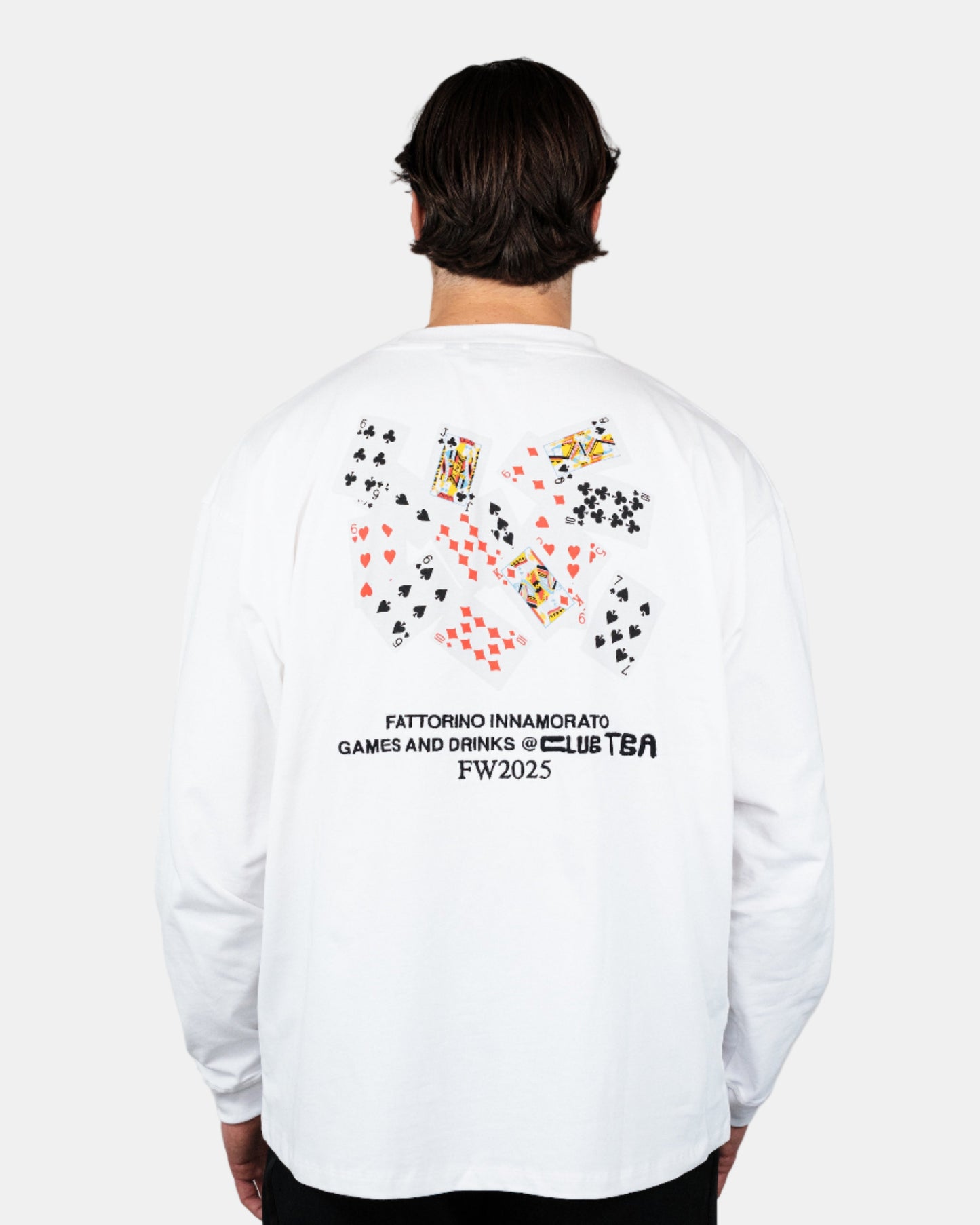 Person wearing a white longsleeve tshirt with colorful graphics and text on the back, standing against a plain background. Play cards longsleeve Fattorino Innamorato