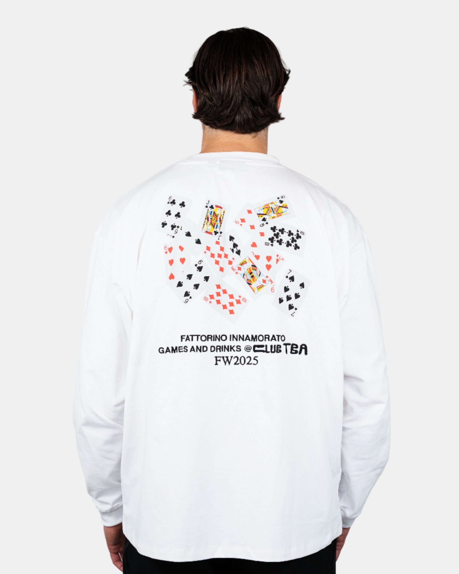 Person wearing a white longsleeve tshirt with colorful graphics and text on the back, standing against a plain background. Play cards longsleeve Fattorino Innamorato