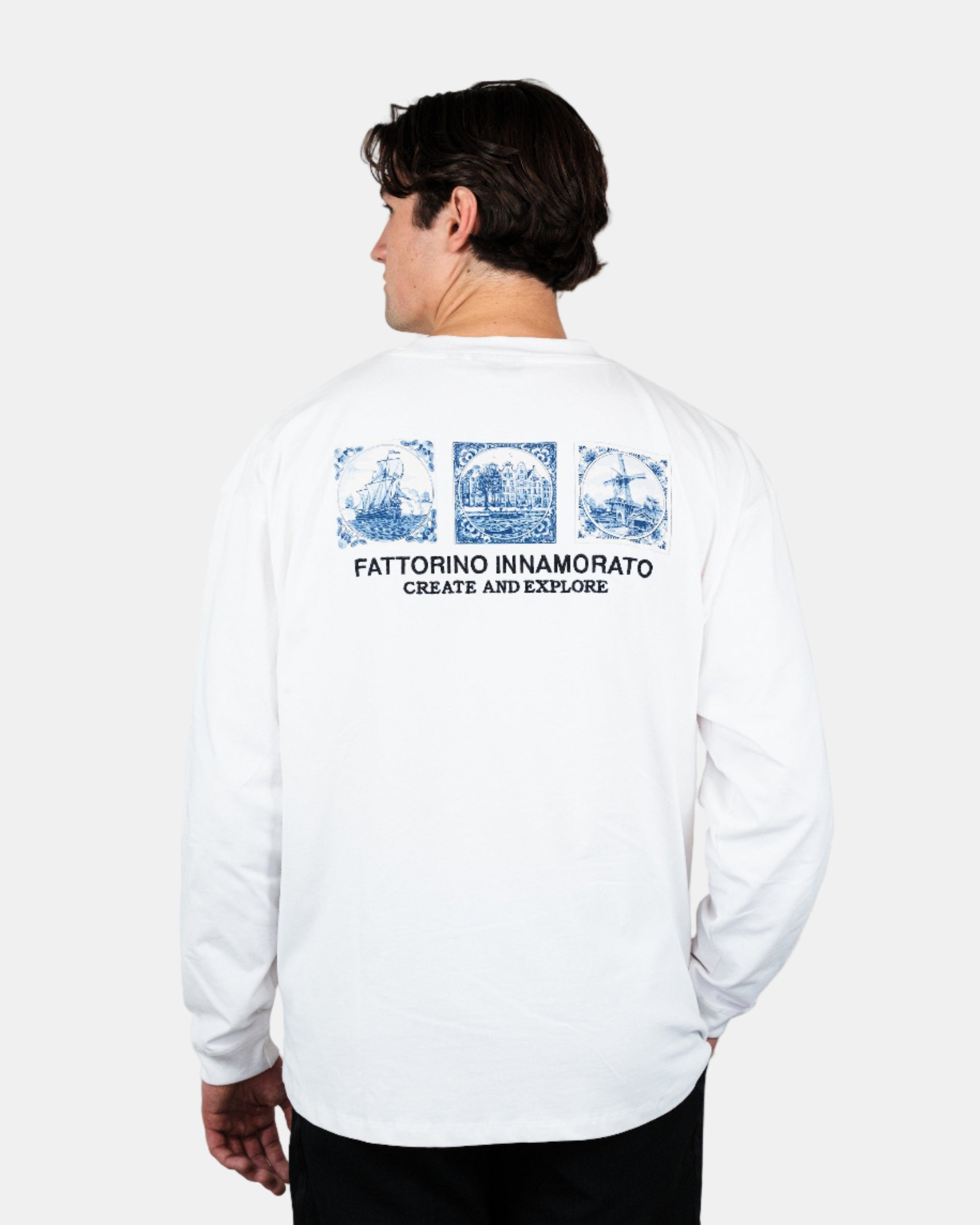 Person wearing a white long-sleeve shirt with graphics and text on the back, standing against a plain background. Fattorino Innamorato Dutch longsleeve