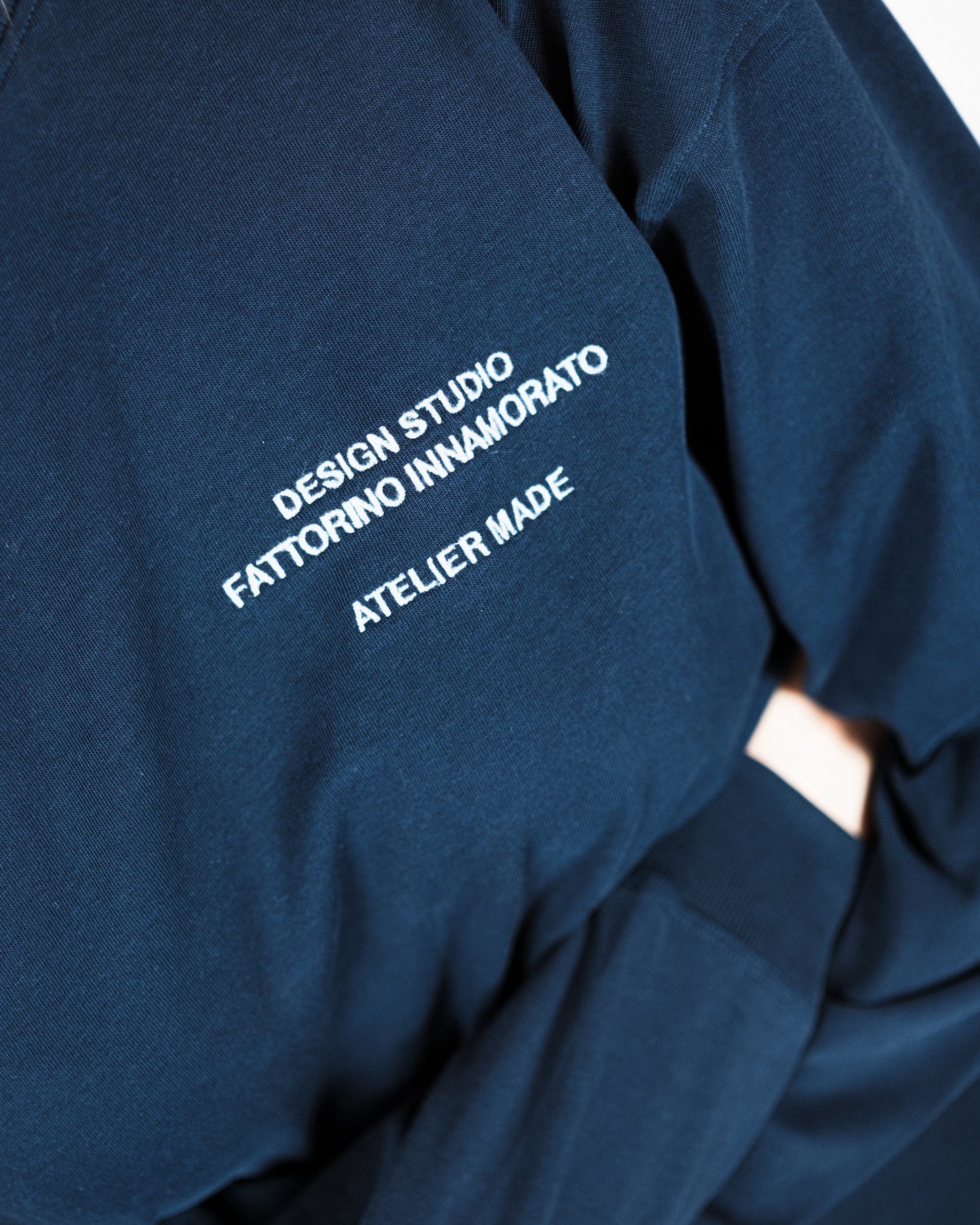 Woman wearing a navy long-sleeve shirt with a logo on a white background. Fattorino Innamorato City Longsleeve