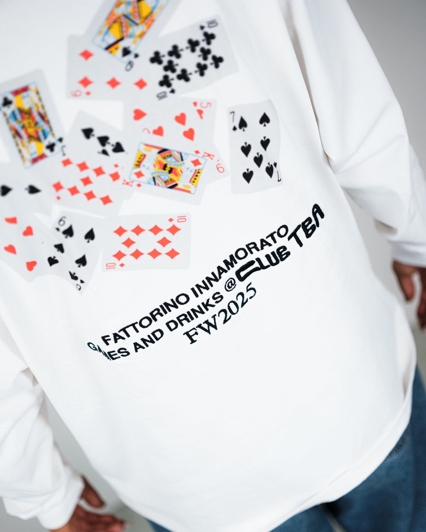 White longsleeve tshirt with playing card design and text on a plain background. Fattorino Innamorato play cards 