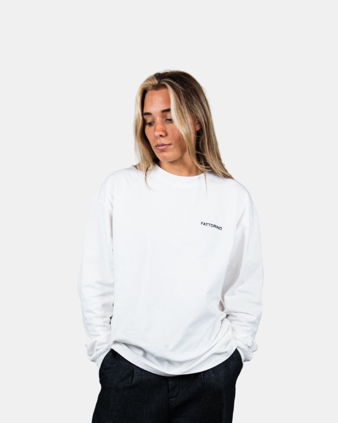 Person wearing a white longsleeve and black pants standing against a plain background. Fattorino Innamorato play cards longsleeve