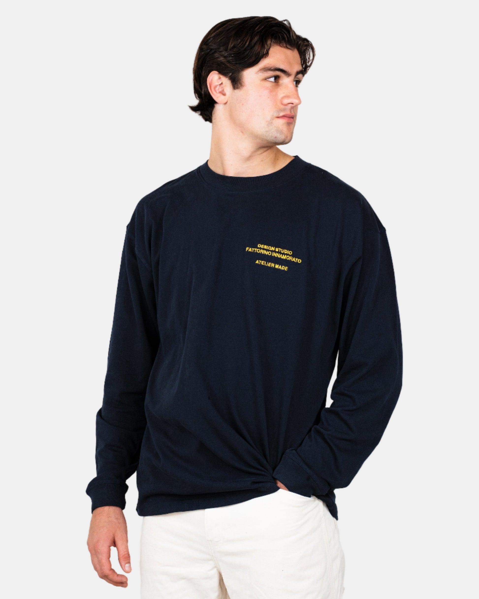 Person wearing a navy longsleeve shirt with yellow text and graphics on the front, standing against a white background. Fattorino Innamorato maison navy longsleeve