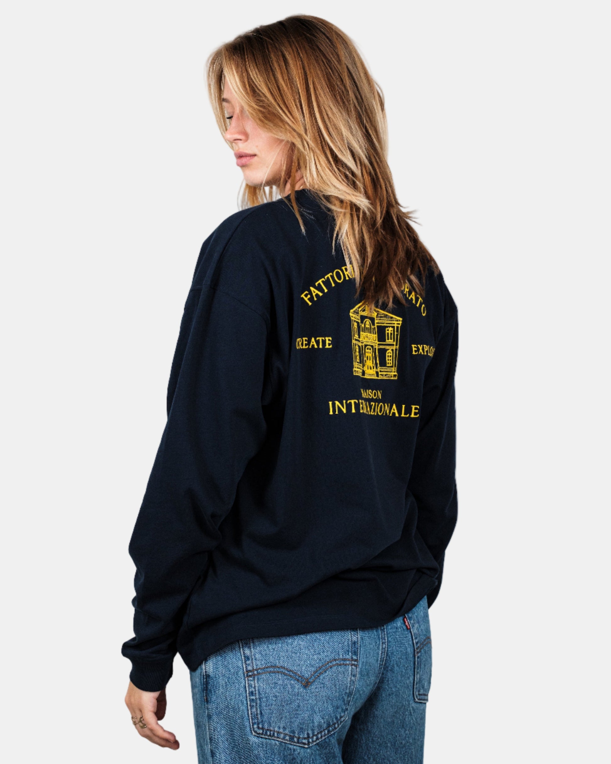 Person wearing a navy longsleeve shirt with yellow text and graphics on the back, standing against a white background. Fattorino Innamorato maison navy longsleeve