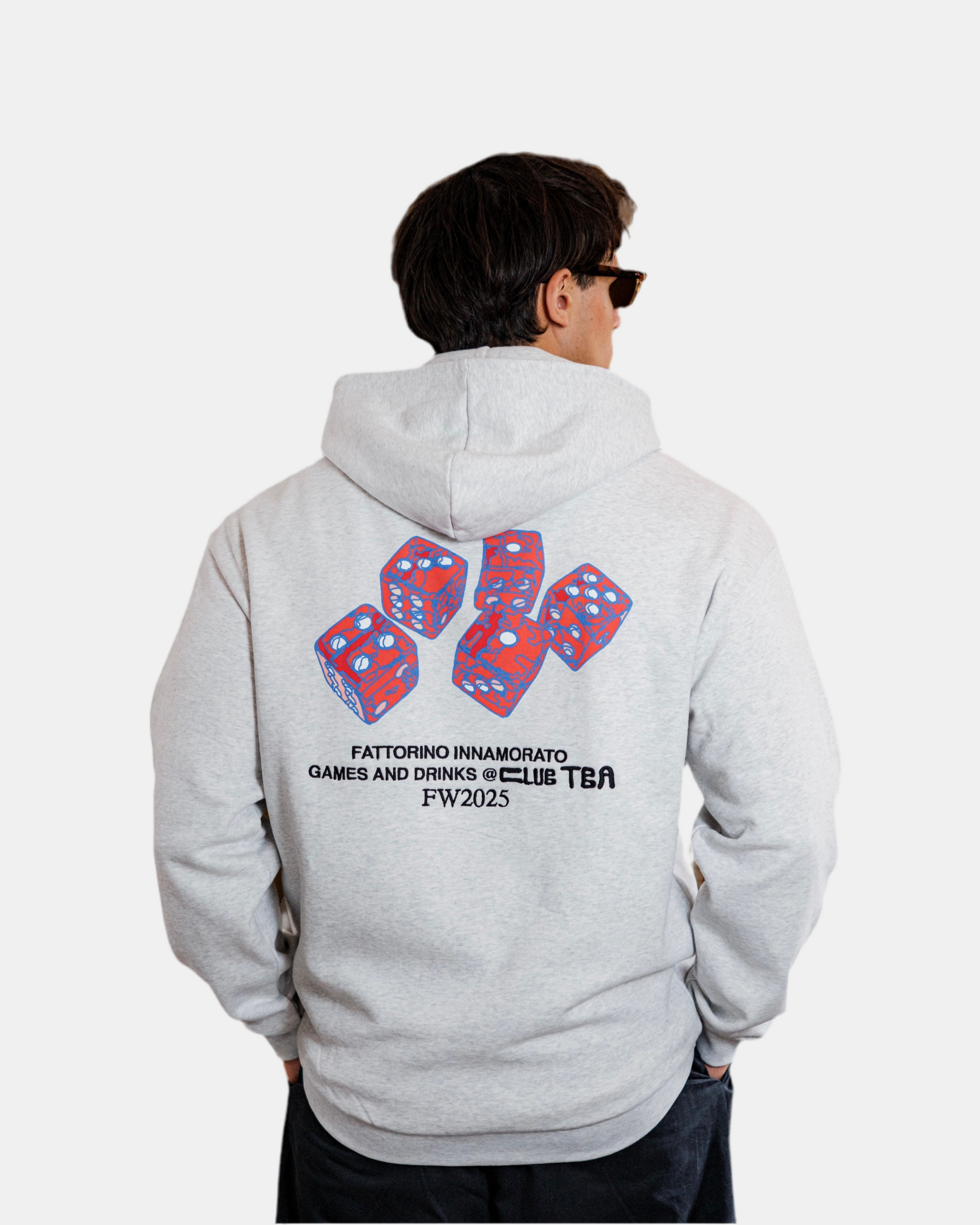 Person wearing a gray hoodie with colorful dice design and text on the back, on a white background. Fattorino Innamorato