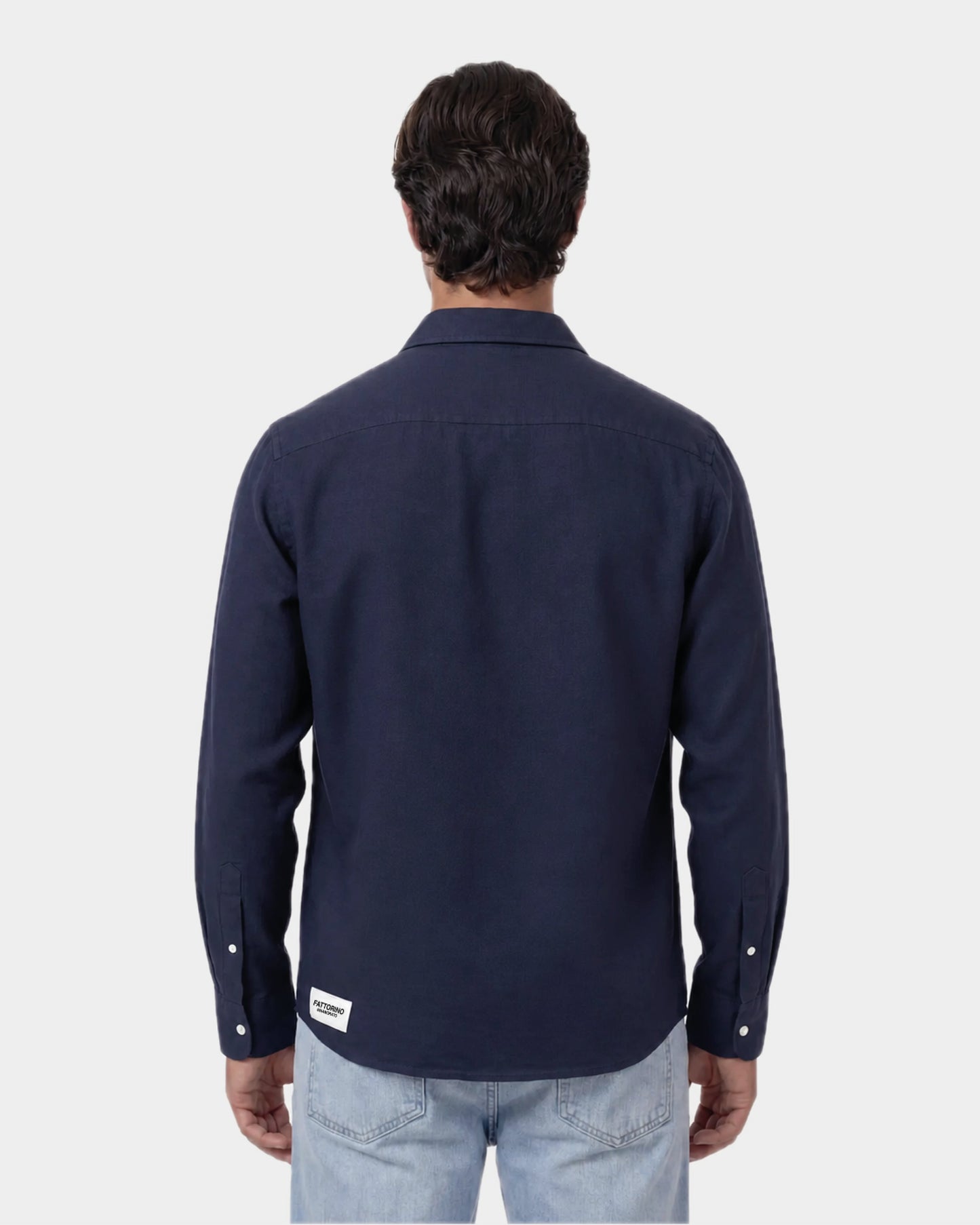 Man wearing a navy button-up shirt and light blue jeans on a white background. Fattorin Innamorato navy cotton shirt. Oxford shirt 