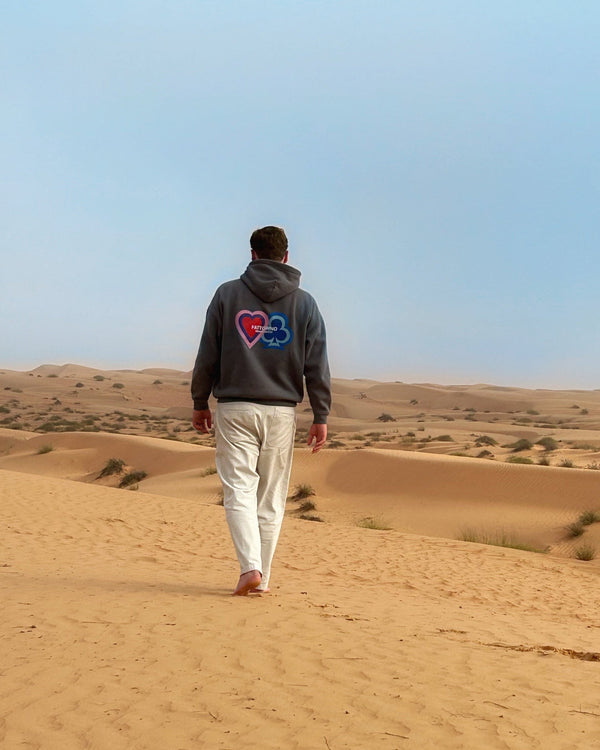 Person walking in a desert landscape with a clear blue sky. Fattorino Innamorato hoodie